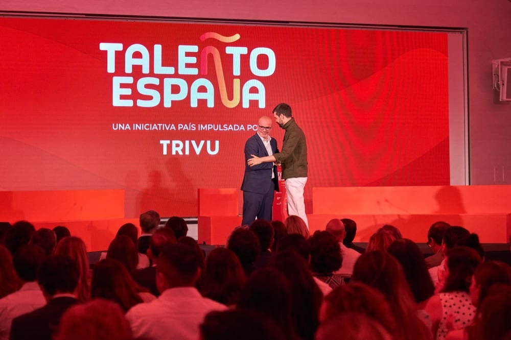 Edición 2026 de TALEÑTO España — abrazo sobre el escenario ante el muro de marca
